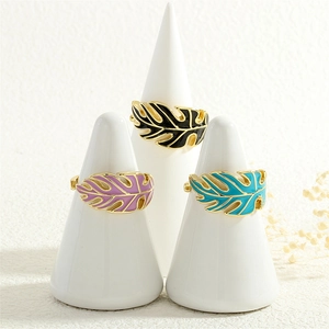 Close-up of tropical monstera leaf rings with colorful enamel and gold-plated finish