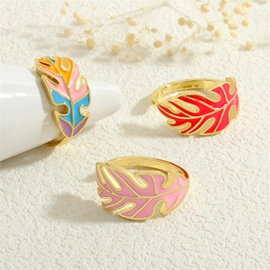 Three enamel leaf rings in rainbow, red and pink finishes on jewelry stands