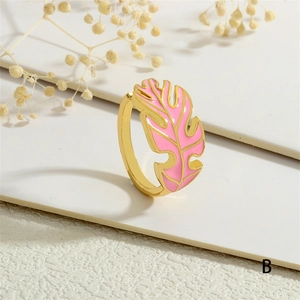 Detail of pink enamel tropical leaf ring in gold finish with geometric background