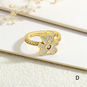 Macro shot of gold-plated open ring with white enamel bear and heart-shaped zircon detail
