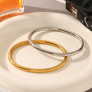Detail of minimalist 18K gold and silver stainless steel bangles with side hinge design