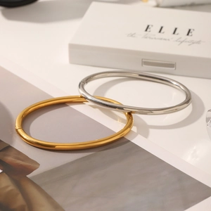 Detailed close-up of polished gold and silver stainless steel bangles in minimalist style