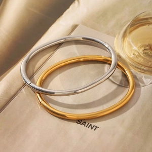 Detail view of 18K gold and silver stainless steel oval hinged bangles on magazine