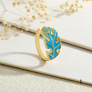 Detail view of a gold-plated leaf ring with blue enamel texture and adjustable open band