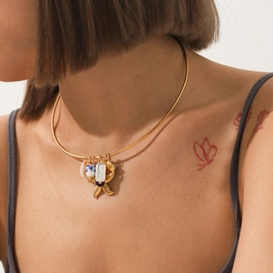 Dettaglio di un choker dorato con ciondoli a vaso di porcellana, madreperla e stella marina