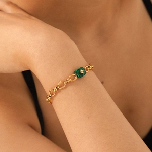 Détail d'un bracelet gourmette doré vintage avec malachite carrée et charm trèfle délicat