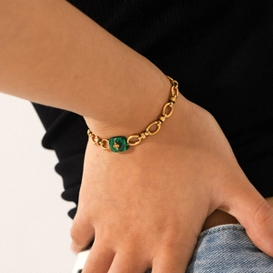 Détail de bracelet chaîne dorée avec malachite carrée et motif floral incrusté