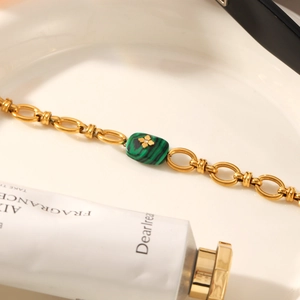Gros plan du bracelet à maillons dorés avec pierre malachite verte et trèfle doré
