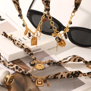 Detail of leopard print fabric and gold chain jewelry with sun and butterfly charms