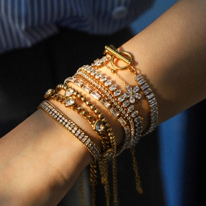 Nahaufnahme von mehrlagigem Goldarmband-Set mit Herzanhängern und Zirkon-Tennisarmband
