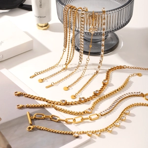 Goldenes Edelstahl-Armband-Set mit Zirkonia-Herz und Gliederketten auf weißem Tisch