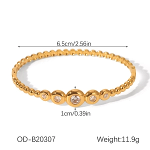 Detailed view of gold stainless steel bangle with five graduated crystal settings