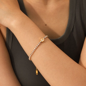 Detalle de una pulsera tennis bañada en oro de 18k con piedra central cuadrada amarilla