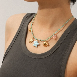 Braided rope necklace with sea star, turtle and goldfish pendants on a model