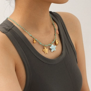 Detail showing woven ocean-themed necklace with starfish, turtle, and shell charms on a model