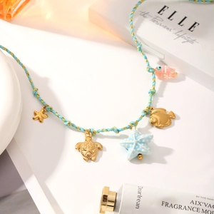 Macro shot of blue woven cord necklace with gold starfish and turtle ocean charms