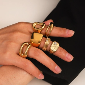 Set of five gold stainless steel rings with geometric designs and zircon on a model's hand
