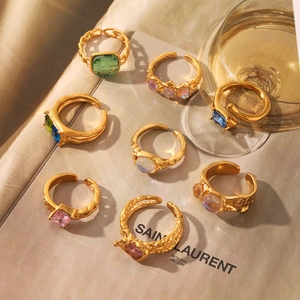Detailed close-up of vintage gold rings with emerald and moonstone inlays on a magazine