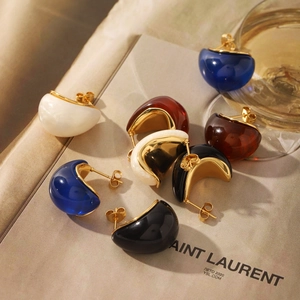 Detailed macro view of retro 18K gold-plated stainless steel resin earrings on a magazine
