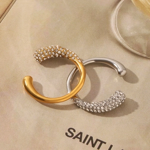 Detailed macro view of crisscross C-shaped rings with sparkling cubic zirconia in gold and silver