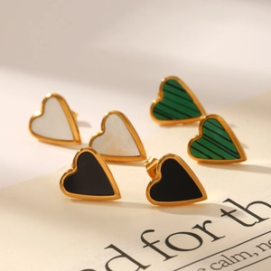 Detail van hartvormige oorknopjes in goud met zwarte, witte en groene steeninleg