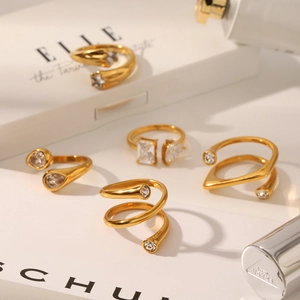 Detailed close-up of various gold-plated stainless steel rings with sparkling crystals