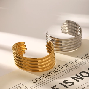 Detail of wide multi-layered stainless steel cuff bracelets in gold and silver finish