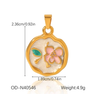 Detail of floral enamel charm with pink flower pattern and golden frame in macro view