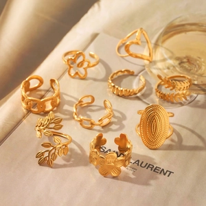 9-piece gold stainless steel ring set with floral, leaf, and heart designs on fabric