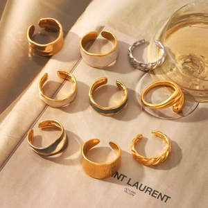 Detail of assorted gold and enamel adjustable open rings under warm sunset lighting