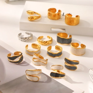 Detail of diverse stainless steel drip oil open rings with gold finish and enamel patterns