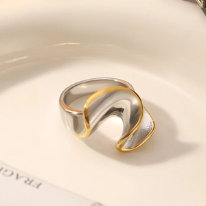 Makroaufnahme der abstrakten gewellten zweifarbigen Edelstahlring in Gold und Silber