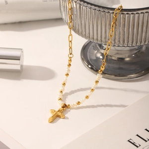 Detailed macro shot of a gold cross pendant necklace with pearls on a magazine background
