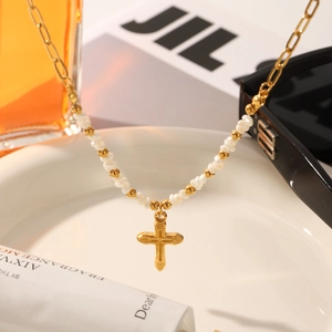 Close-up of gold cross pendant with baroque pearls and asymmetric chain necklace