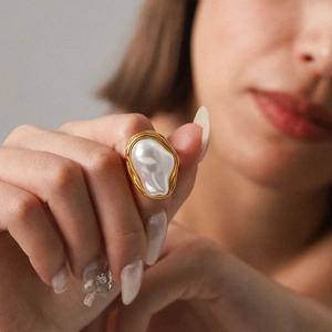 Gold stainless steel baroque pearl ring featuring unique textured geometric design on finger