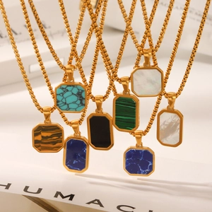 Detailed macro view of various gemstone pendants on gold box chains featuring malachite and onyx
