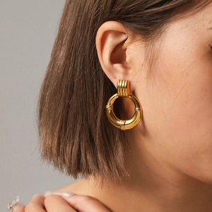 Detail of vintage 18K gold hoop earrings with polished finish and groove texture on model