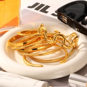 Macro shot of gold stainless steel bangle set with wave and bamboo textures in a dish
