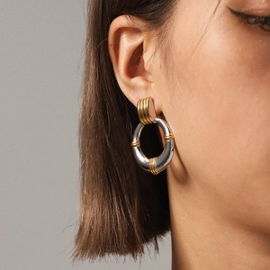 Detail of mixed-metal hoop earrings in gold and silver finish on a model