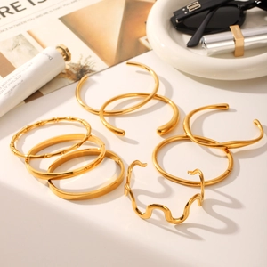 Flat lay of multiple gold-plated stainless steel bangles with diverse textures and finishes