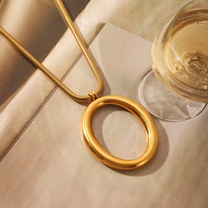 Detail shot of a golden snake chain necklace with a large polished oval pendant