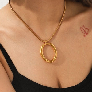 Minimalist gold snake chain necklace featuring a large oval pendant on model