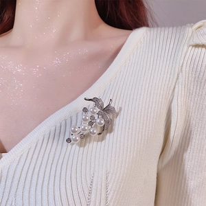 Eleganter Trauben-Anstecker mit weißen Perlen und Zirkonia auf einem Strickpullover