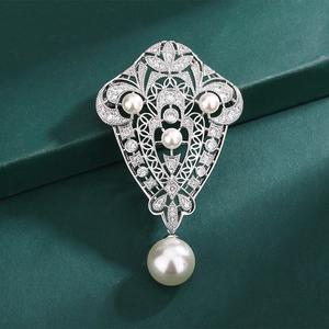 Silberne Brosche im Barockstil mit Perlen und Strass auf dunkelgrünem Hintergrund