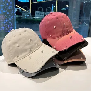 Detail of distressed baseball cap featuring pearl embellishments in multiple colors