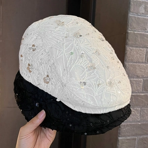 Close-up of intricate floral embroidery and sequins on black and white mesh berets