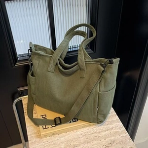 Detail view of green corduroy tote bag showing side pockets and textured fabric