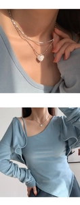 Detail of 925 silver heart pendant necklace with shimmering crystals on blue knitwear