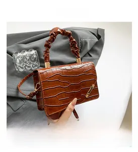 Close-up of brown crocodile texture bag with pleated handle and gold metal detail