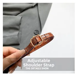 Close-up of adjustable brown crocodile pattern strap with a golden metal buckle